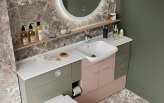 Bathroom with green and blush fitted furniture, marble walls and floors, and round LED mirror