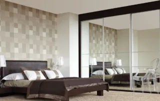 Modern bedroom with mirrored sliding wardrobe and feature wall in neutral tones Modern bedroom with mirrored sliding wardrobe and feature wall in neutral tones