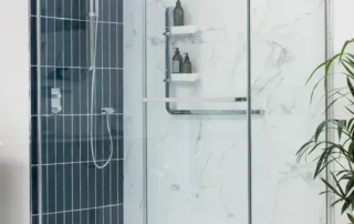 Sliding glass shower enclosure with recessed storage and white marble walls