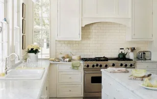 Bright classic kitchen with white marble countertops, subway tile backsplash, and farmhouse sink