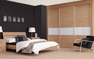 Contemporary bedroom with wooden furniture, white bedding, and sliding wardrobe with white glass panels Contemporary bedroom with wooden furniture, white bedding, and sliding wardrobe with white glass panels