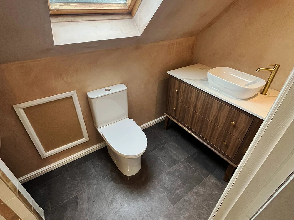 Loft bathroom with wall-hung toilet, wood vanity and skylight