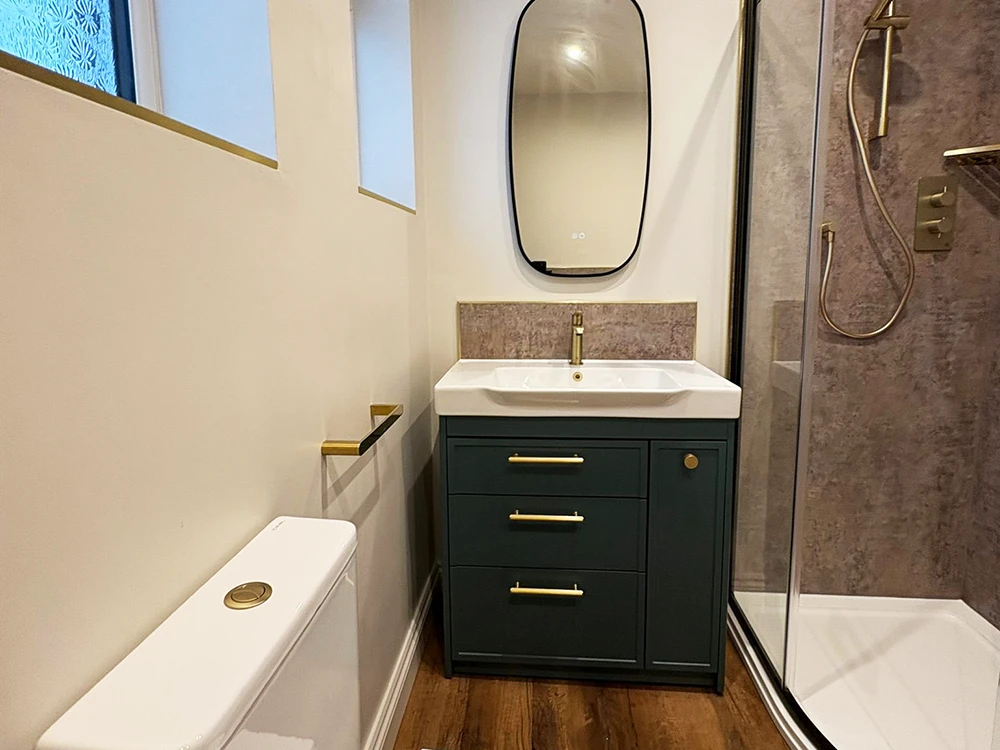 bathroom with green vanity brushed brass tap toilet and black framed quadrant shower enclosure