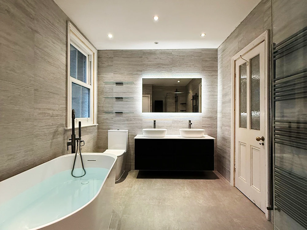 modern bathroom with freestanding bath gunmetal fixtures double vanity and illuminated mirror
