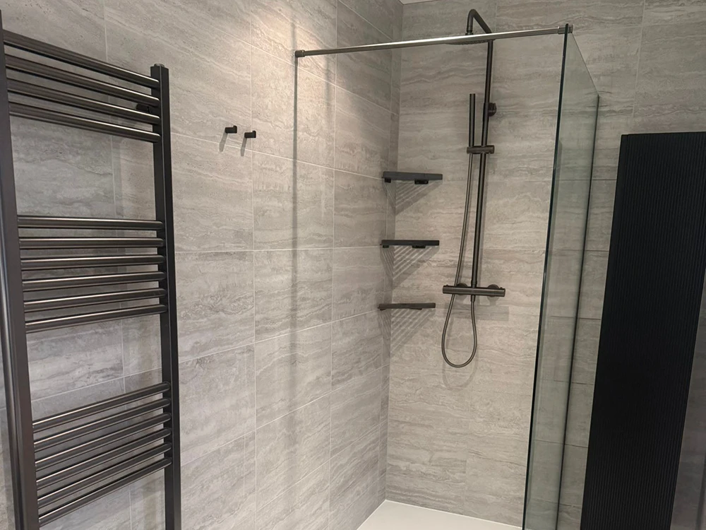 walk in shower with gunmetal fixtures glass panel and heated towel rail