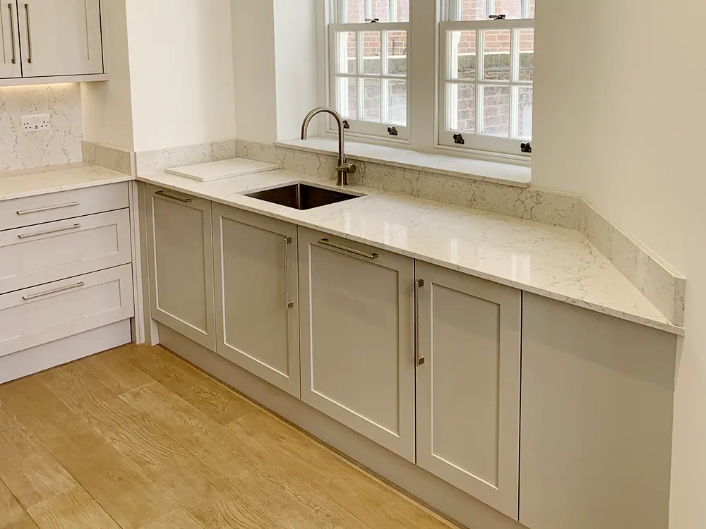 Installed apartment kitchen with limestone cabinetry, Algarve worktops, undermount sink, and Bosch cooking appliances
